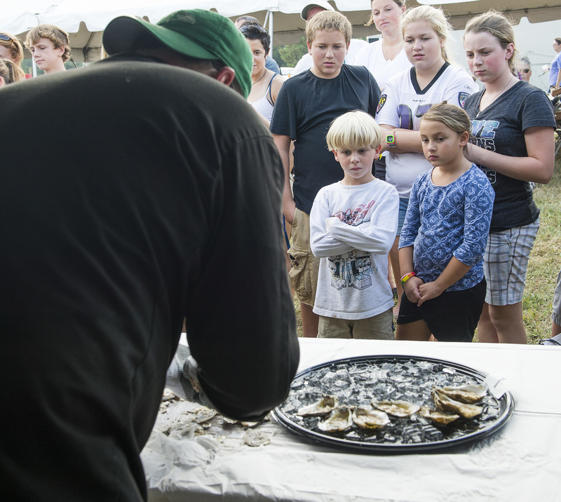 Shown (l-r) Austin Ortel, Amber Lee Ortel, Brianna Watts Alayna Ortel and Coen Watts watch Thomas Watts as he shucks oysters in the oyster shucking contest. BY DENY HOWETH